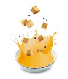 Image of Croutons falling into bowl of soup against white background