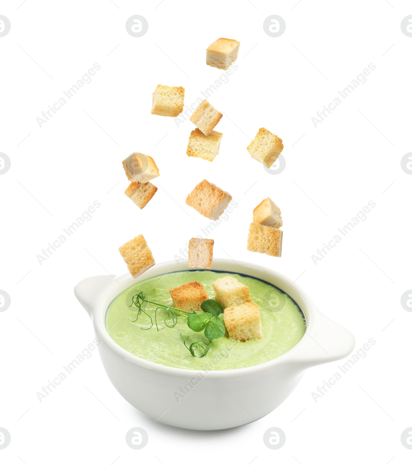 Croutons falling into bowl of soup against white background Image of Croutons falling into bowl of soup against white background