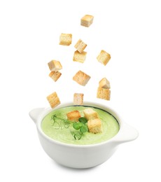 Image of Croutons falling into bowl of soup against white background