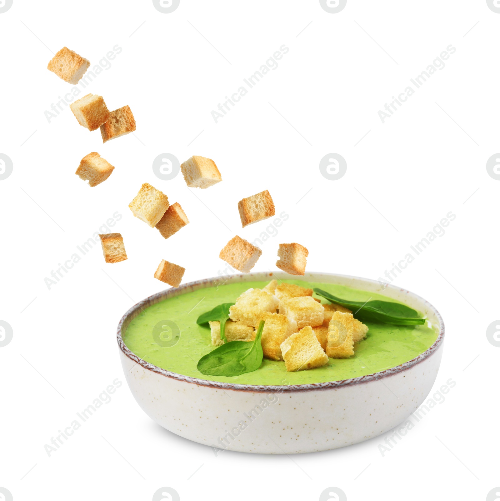 Croutons falling into bowl of soup against white background Image of Croutons falling into bowl of soup against white background