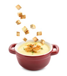 Image of Croutons falling into bowl of soup against white background