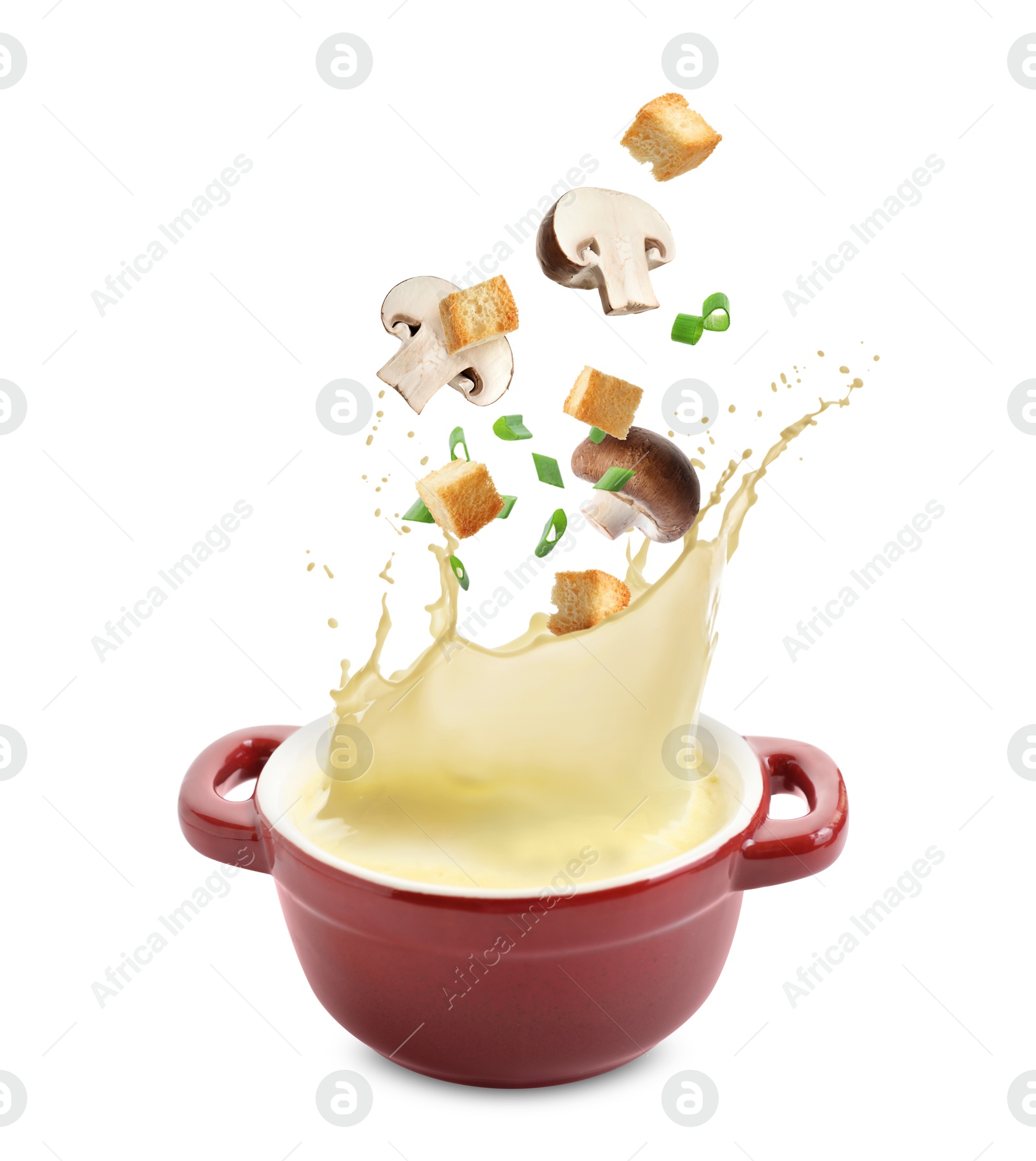 Image of Croutons and mushrooms falling into bowl of soup against white background