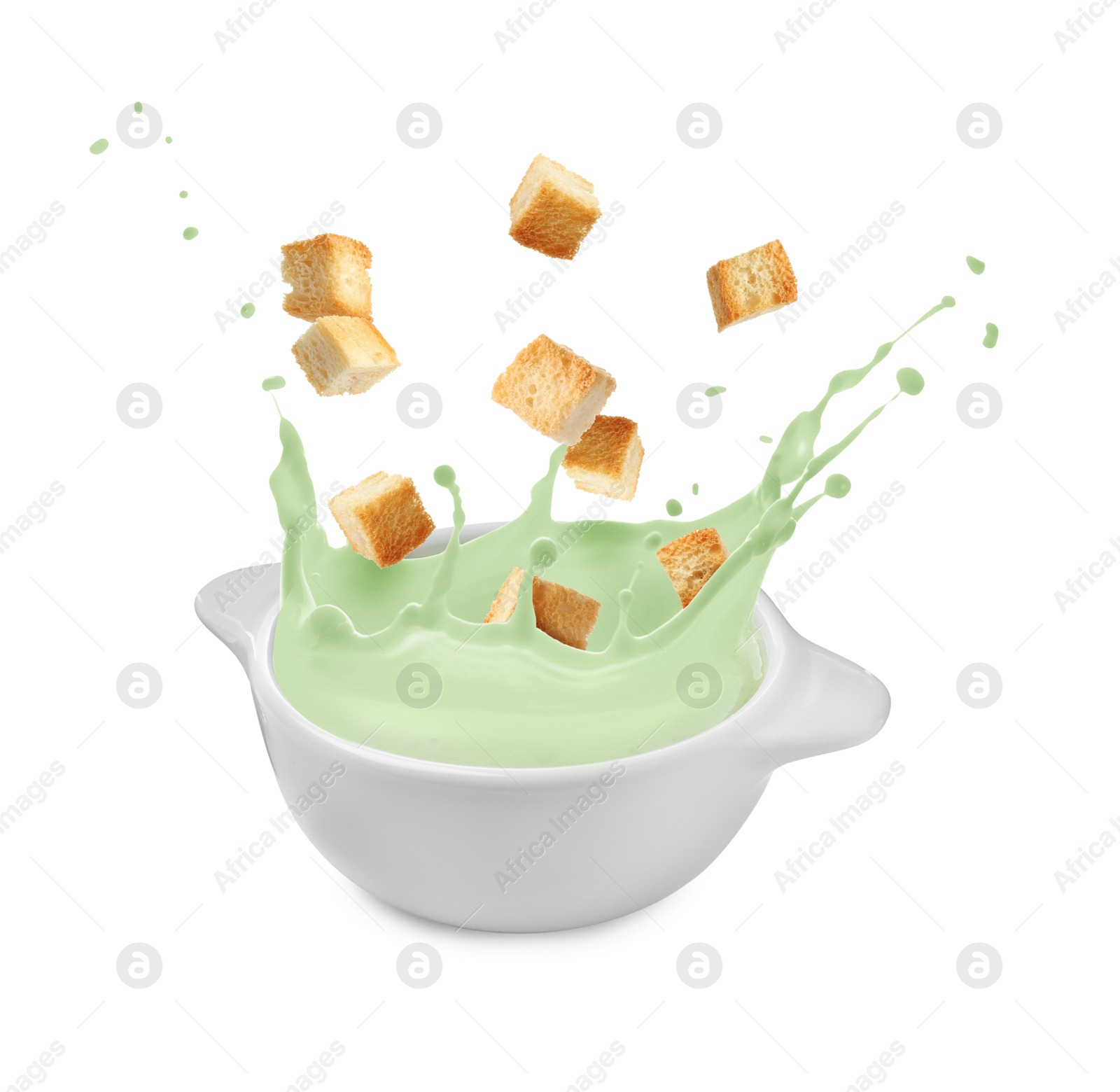 Image of Croutons falling into bowl of soup against white background