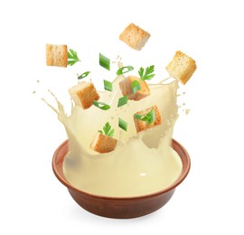 Image of Croutons and herbs falling into bowl of soup against white background
