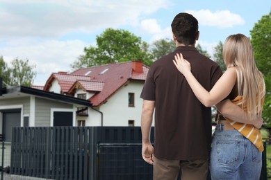 Image of Couple looking at their house outdoors, back view