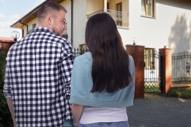 Image of Couple looking at their house outdoors, back view