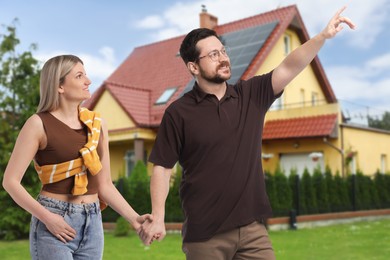 Image of Happy couple near their house outdoors. Real estate ownership