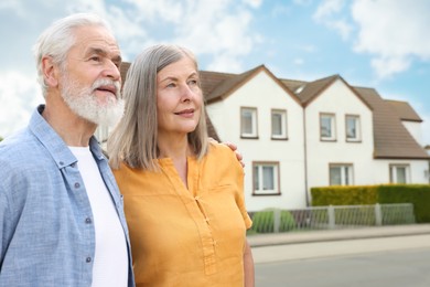Image of Senior couple near their house outdoors. Real estate ownership