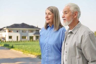 Image of Senior couple near their house outdoors. Real estate ownership