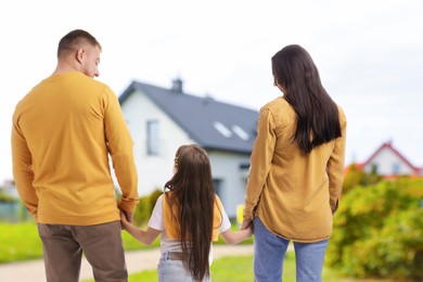 Image of Family with child looking at their house outdoors, back view