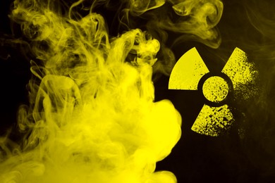 Image of Radioactive sign and yellow toxic smoke against black background