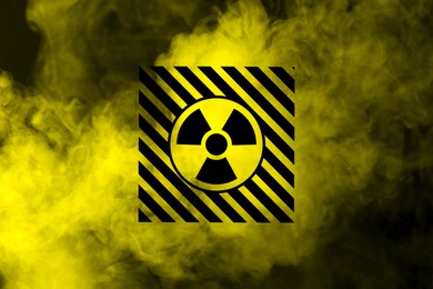 Image of Radioactive sign and yellow toxic smoke against black background