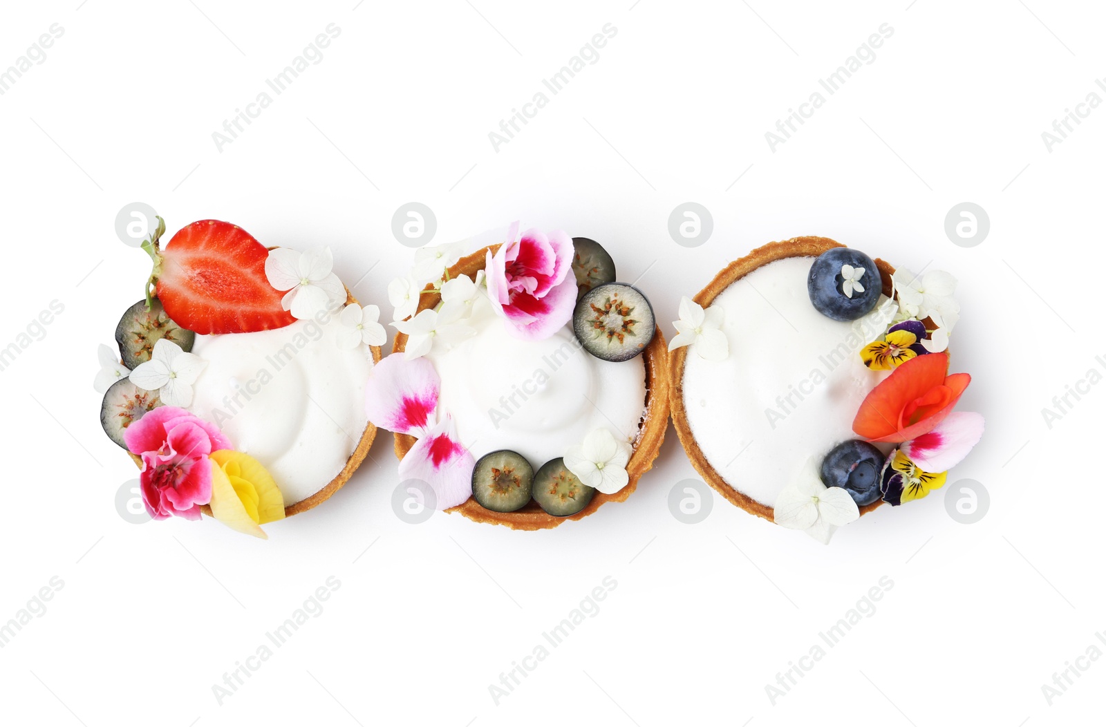 Delicious dessert. Tartlets with cream, berries and flowers isolated on white, top view Photo of Delicious dessert. Tartlets with cream, berries and flowers isolated on white, top view