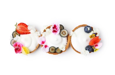 Photo of Delicious dessert. Tartlets with cream, berries and flowers isolated on white, top view