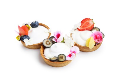 Photo of Delicious dessert. Tartlets with cream, berries and flowers isolated on white