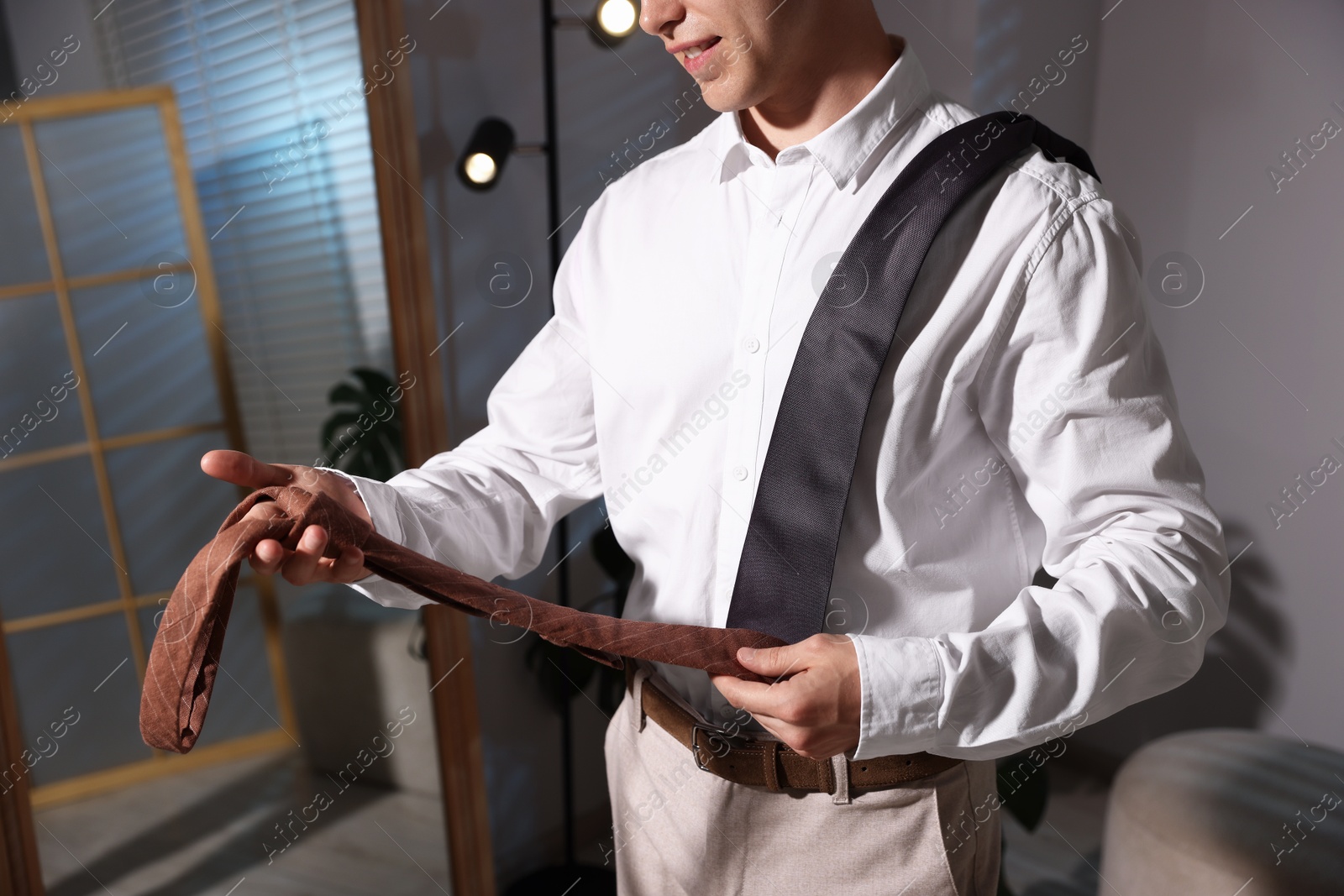 Man choosing neckties while getting ready near mirror indoors, closeup Photo of Man choosing neckties while getting ready near mirror indoors, closeup