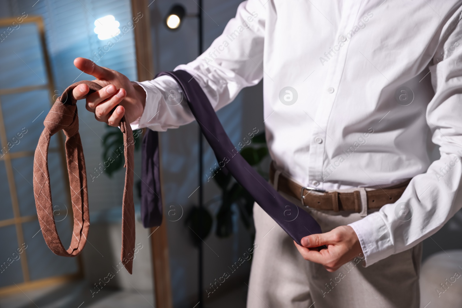 Man choosing neckties while getting ready near mirror indoors, closeup Photo of Man choosing neckties while getting ready near mirror indoors, closeup