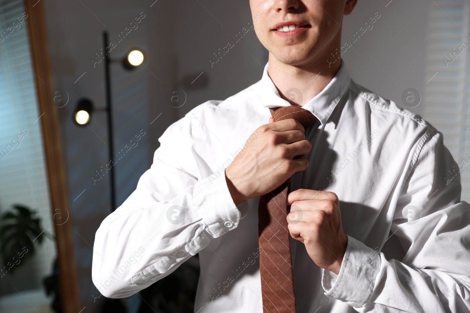 Man adjusting necktie while getting ready indoors, closeup Photo of Man adjusting necktie while getting ready indoors, closeup