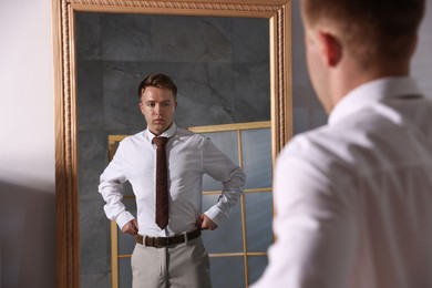 Photo of Handsome man getting ready near mirror indoors