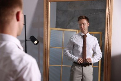 Photo of Handsome man getting ready near mirror indoors