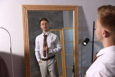 Photo of Handsome man getting ready near mirror indoors