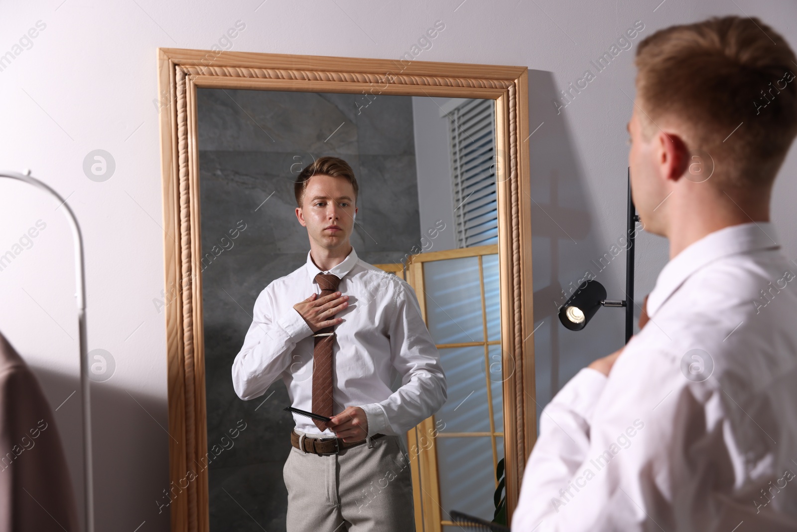 Handsome man brushing his hair while getting ready near mirror indoors Photo of Handsome man brushing his hair while getting ready near mirror indoors