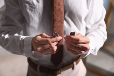 Photo of Man with cufflinks getting ready indoors, closeup