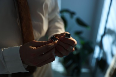 Photo of Man with cufflinks getting ready indoors, closeup. Space for text