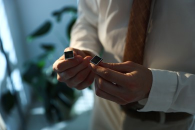 Photo of Man with cufflinks getting ready indoors, closeup. Space for text