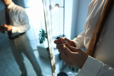 Photo of Man with cufflinks getting ready near mirror indoors, closeup