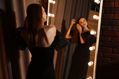 Photo of Beautiful woman getting ready near mirror indoors