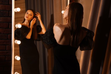 Photo of Beautiful woman getting ready near mirror indoors