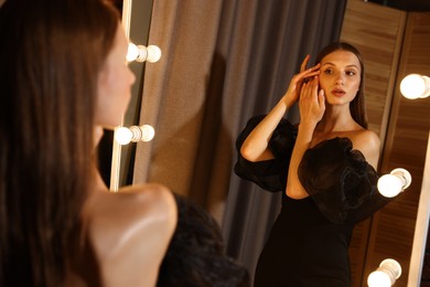 Photo of Beautiful woman getting ready near mirror indoors