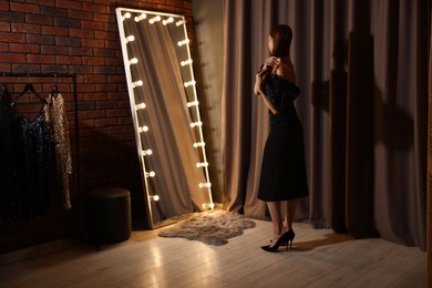 Photo of Beautiful woman getting ready near mirror indoors