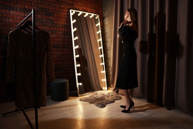 Photo of Beautiful woman getting ready near mirror indoors