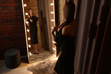 Photo of Woman brushing her hair while getting ready near mirror indoors