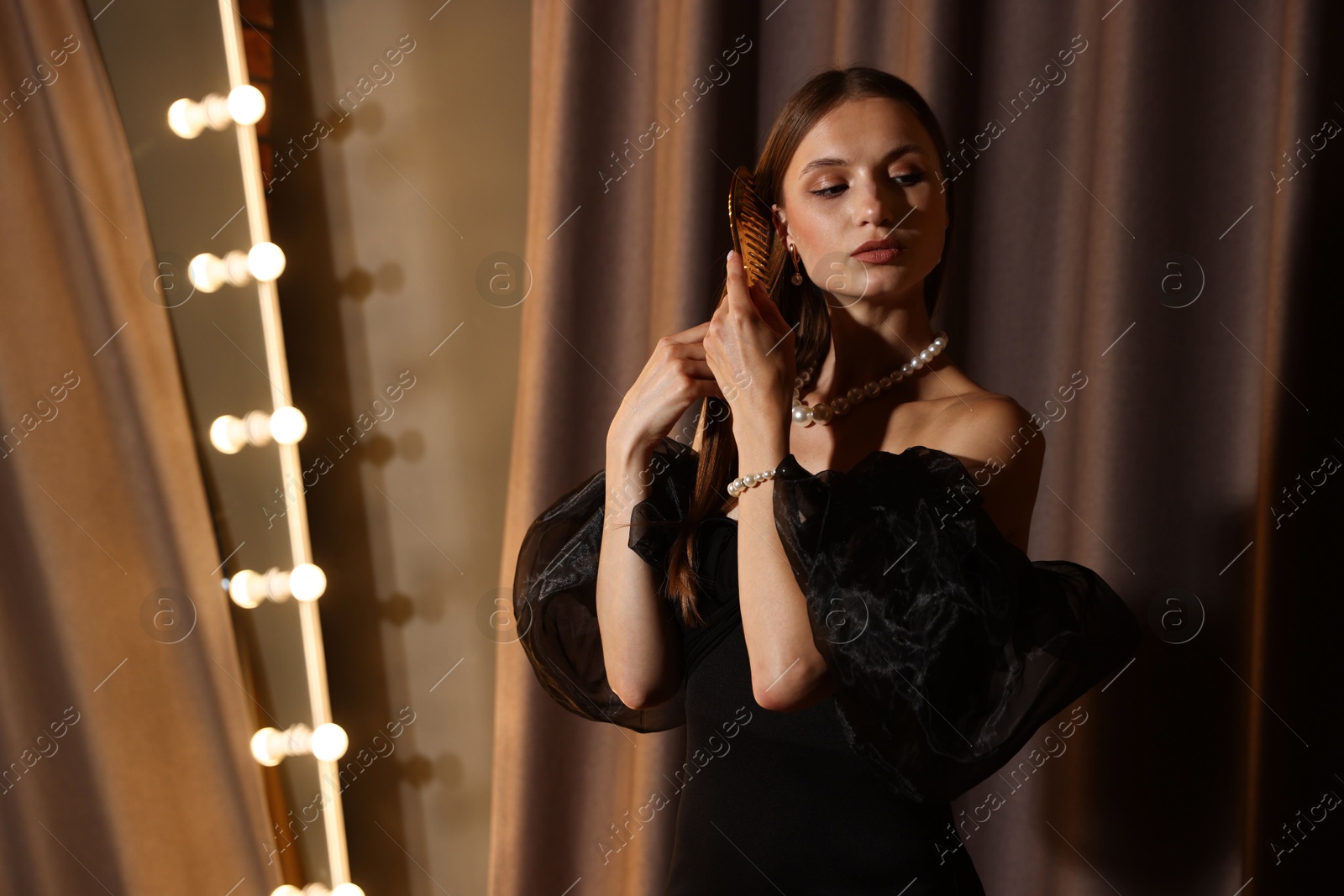 Beautiful woman brushing her hair while getting ready near mirror indoors Photo of Beautiful woman brushing her hair while getting ready near mirror indoors