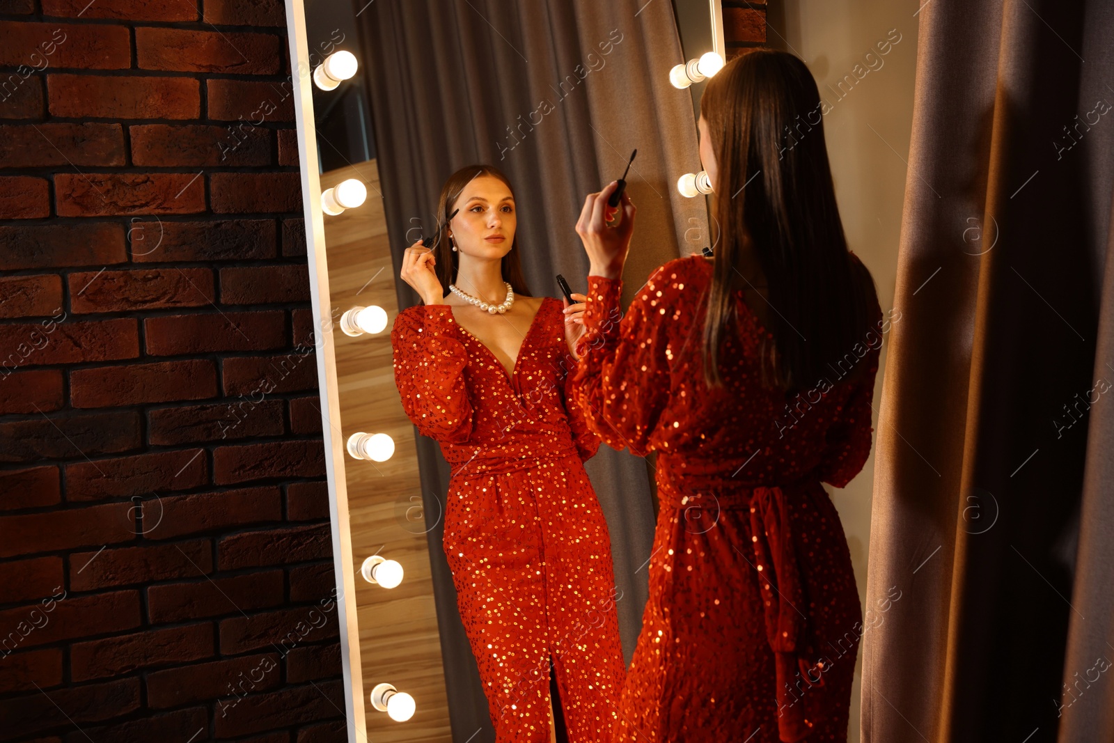 Beautiful woman applying mascara while getting ready near mirror indoors Photo of Beautiful woman applying mascara while getting ready near mirror indoors