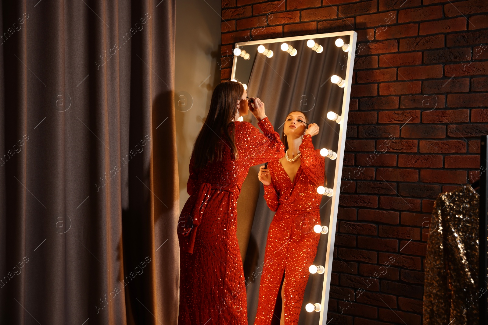 Beautiful woman applying mascara while getting ready near mirror indoors Photo of Beautiful woman applying mascara while getting ready near mirror indoors