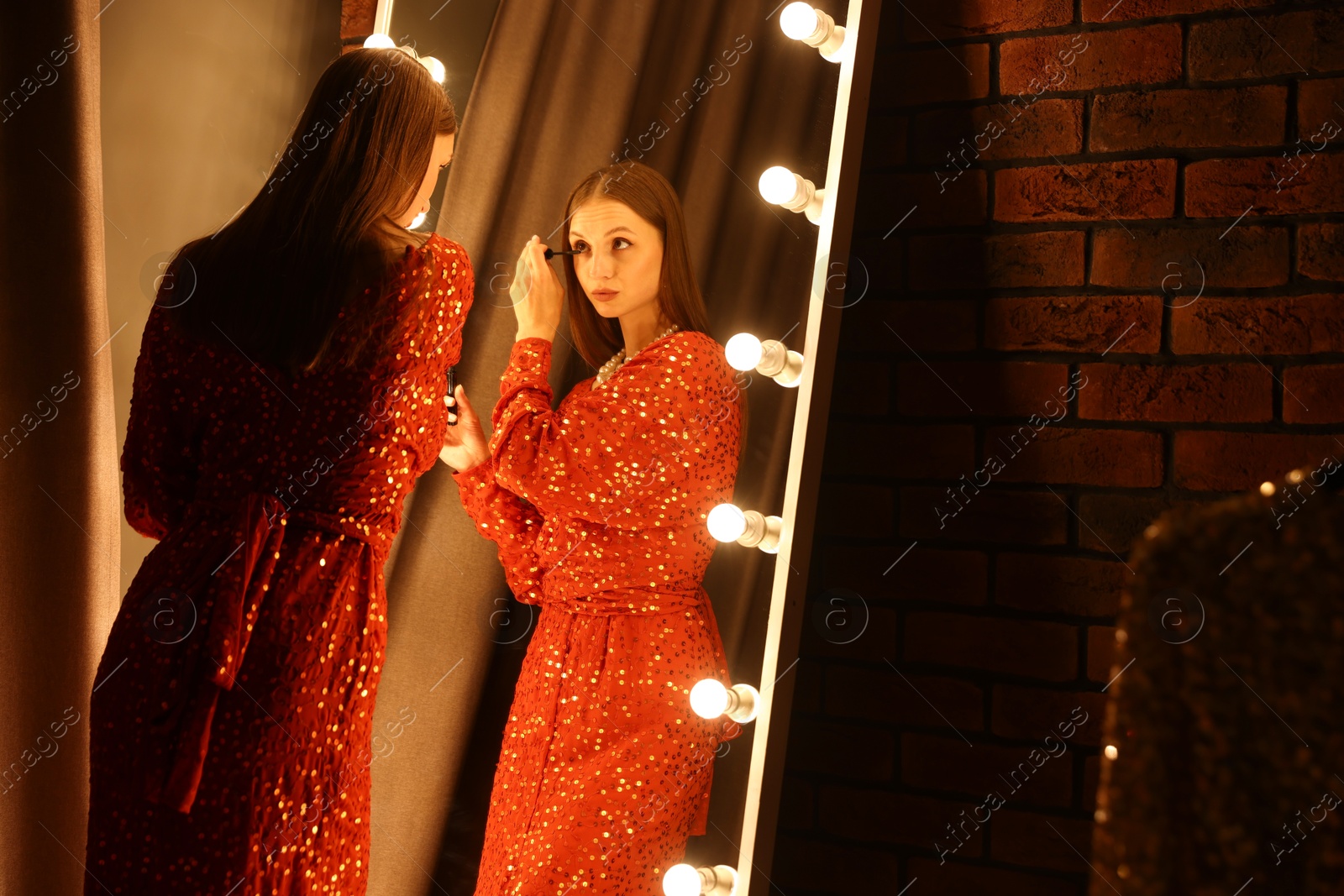 Beautiful woman applying mascara while getting ready near mirror indoors Photo of Beautiful woman applying mascara while getting ready near mirror indoors