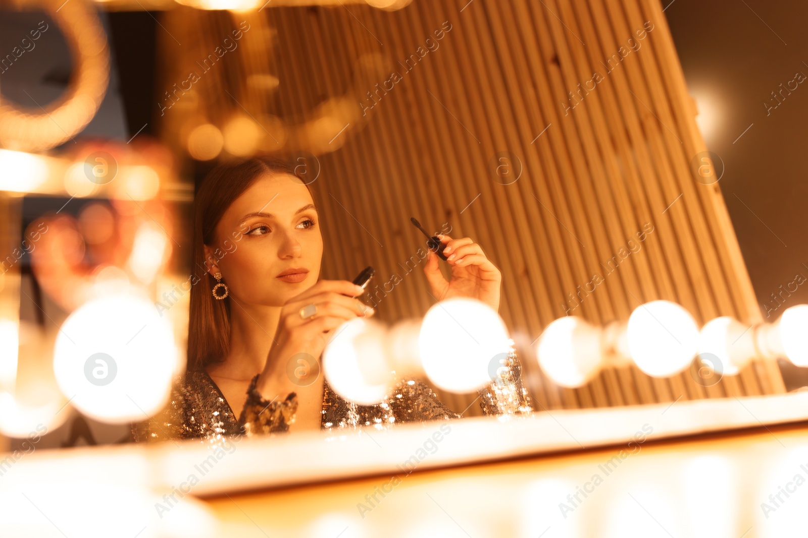 Beautiful woman applying mascara while getting ready near mirror indoors Photo of Beautiful woman applying mascara while getting ready near mirror indoors