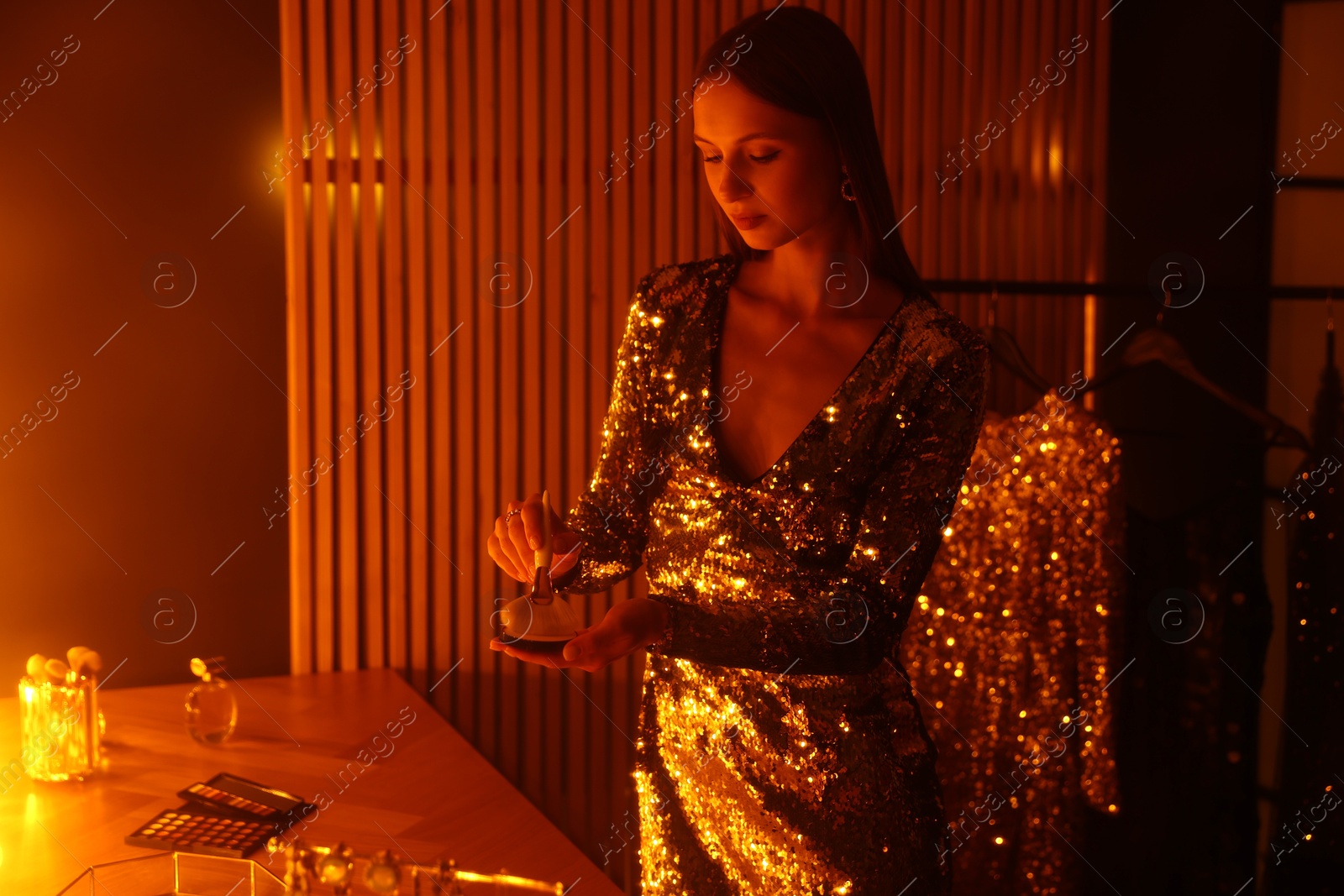 Beautiful woman applying makeup while getting ready at dressing table indoors Photo of Beautiful woman applying makeup while getting ready at dressing table indoors