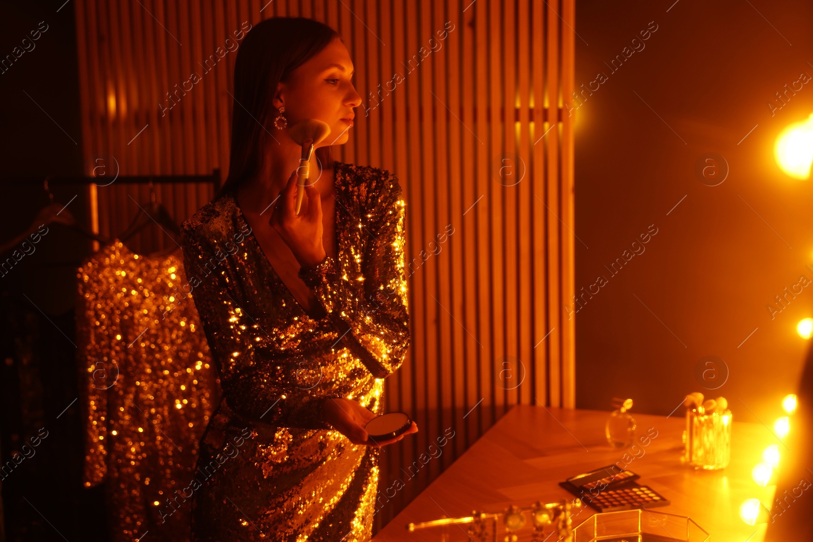 Beautiful woman applying makeup while getting ready at dressing table indoors Photo of Beautiful woman applying makeup while getting ready at dressing table indoors