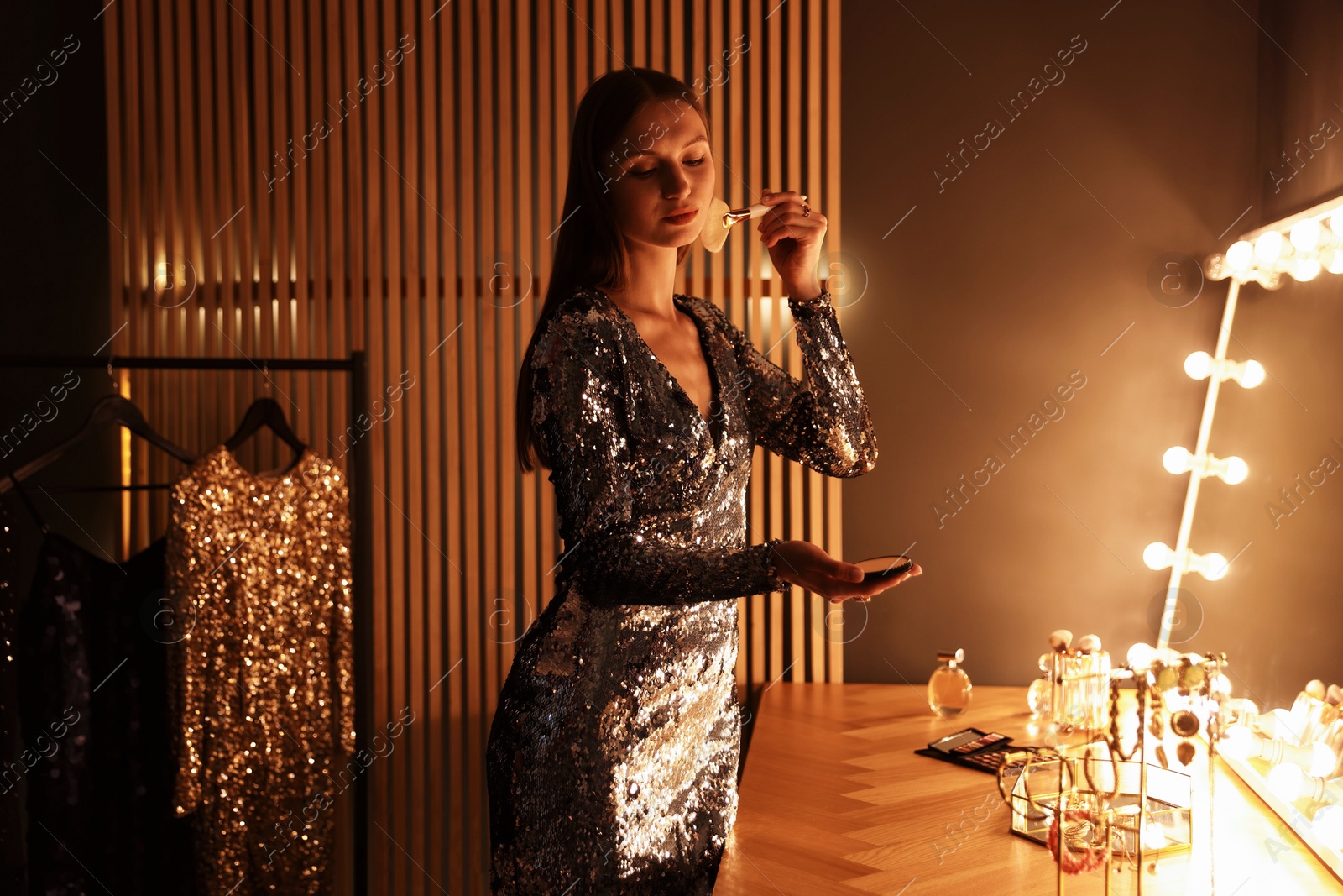 Beautiful woman applying makeup while getting ready at dressing table indoors Photo of Beautiful woman applying makeup while getting ready at dressing table indoors