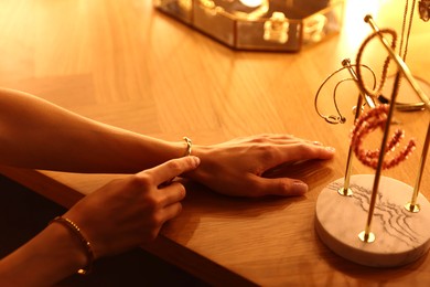 Photo of Woman wearing beautiful bracelet while getting ready at dressing table indoors, closeup