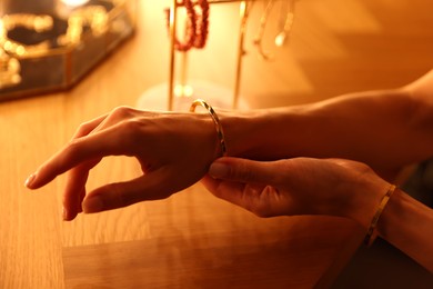 Photo of Woman wearing beautiful bracelet while getting ready at dressing table indoors, closeup