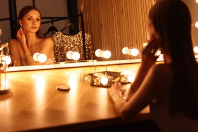 Photo of Beautiful woman getting ready at dressing table indoors