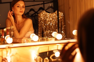 Photo of Beautiful woman getting ready at dressing table indoors