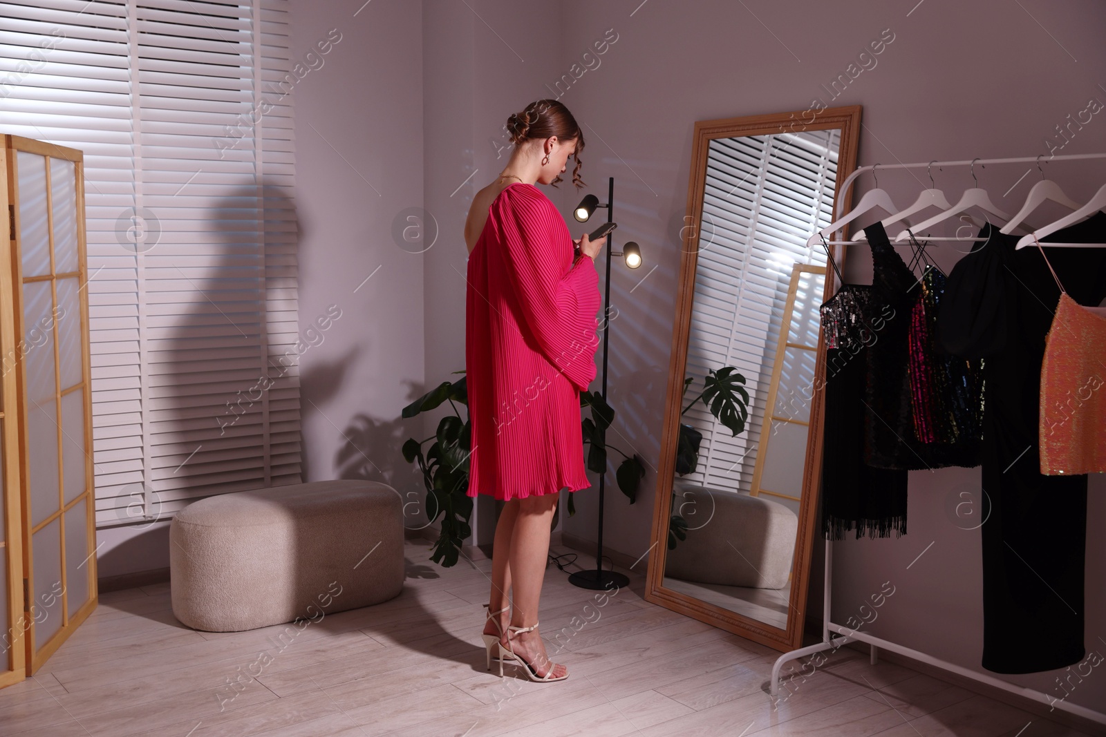 Beautiful woman with smartphone getting ready near mirror indoors Photo of Beautiful woman with smartphone getting ready near mirror indoors