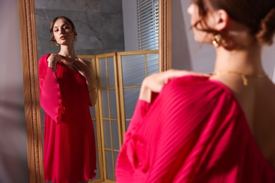 Photo of Beautiful woman getting ready near mirror indoors